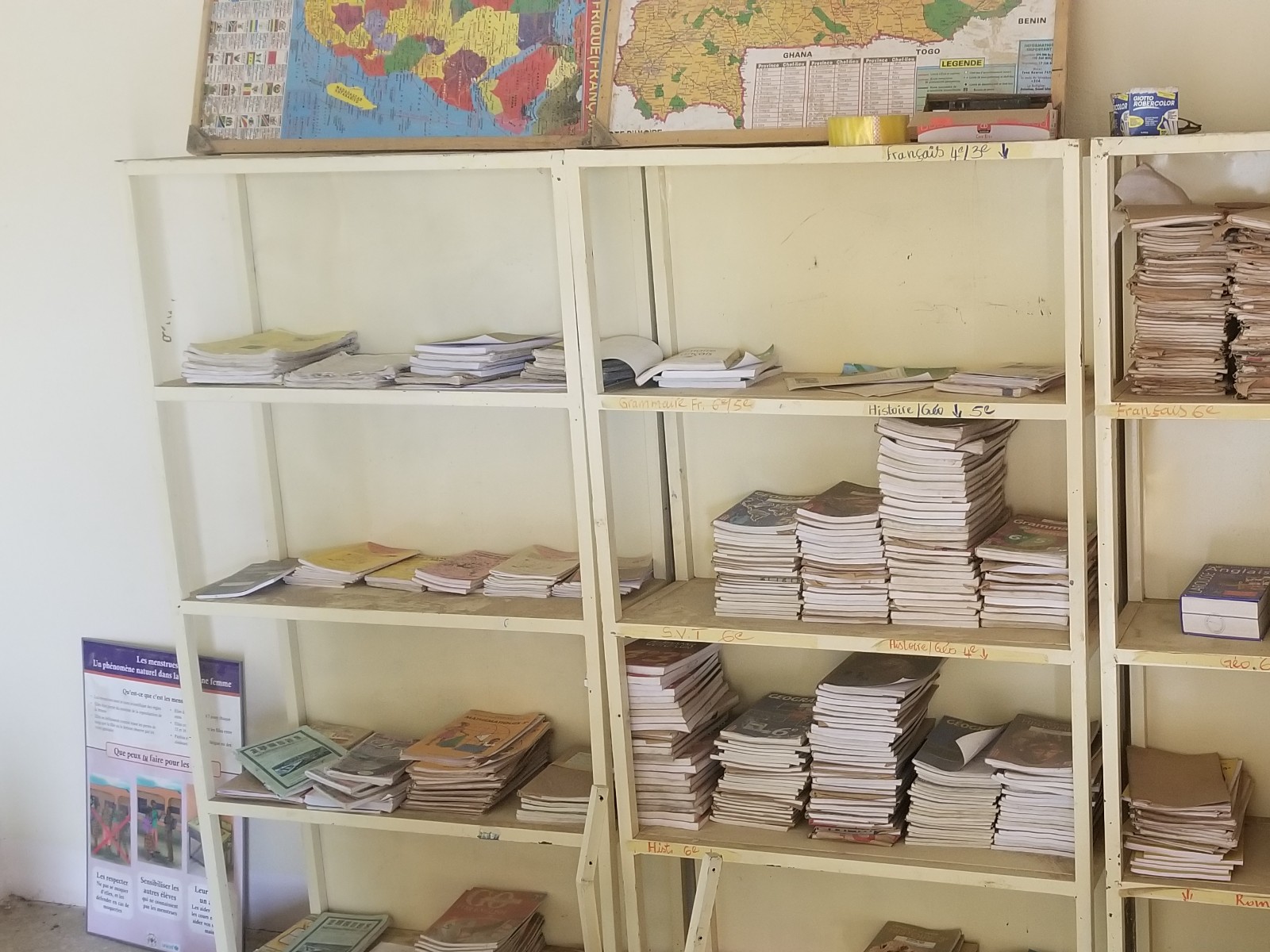 Metal shelves holding the village school's limited, well-worn supply of shared textbooks for every grade and subject
